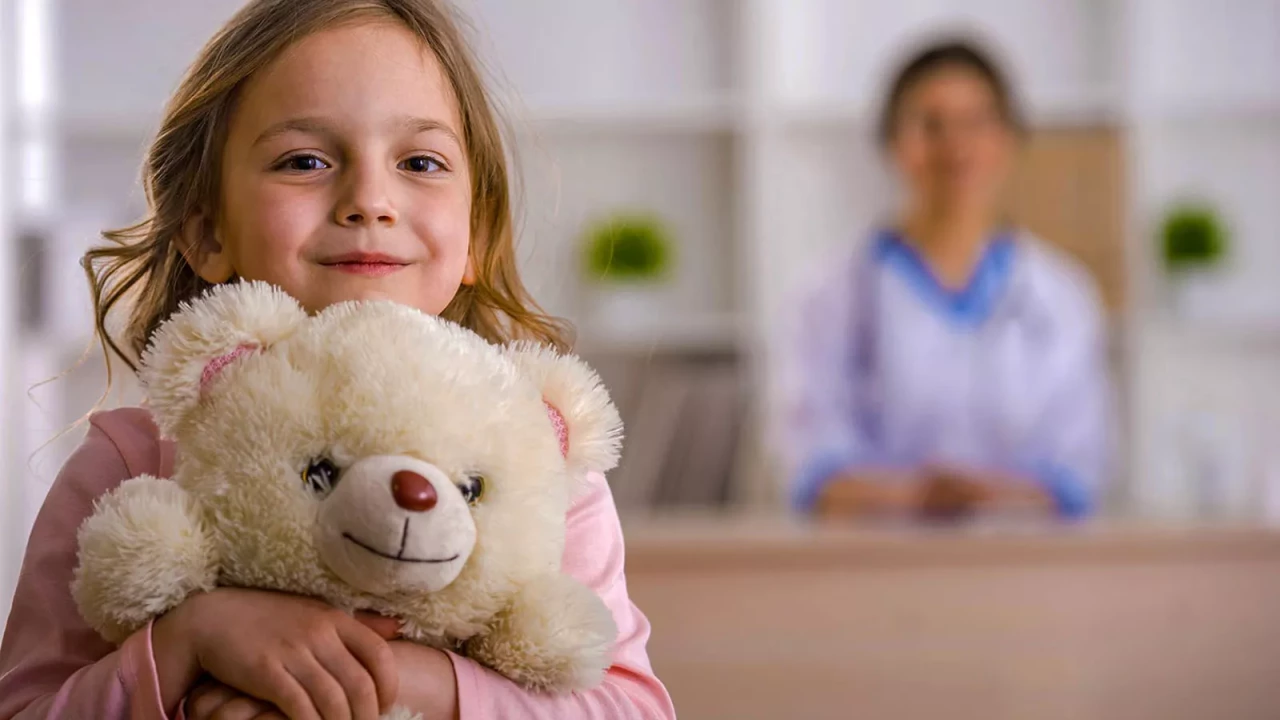 Child holding teddy bear in a healthcare setting